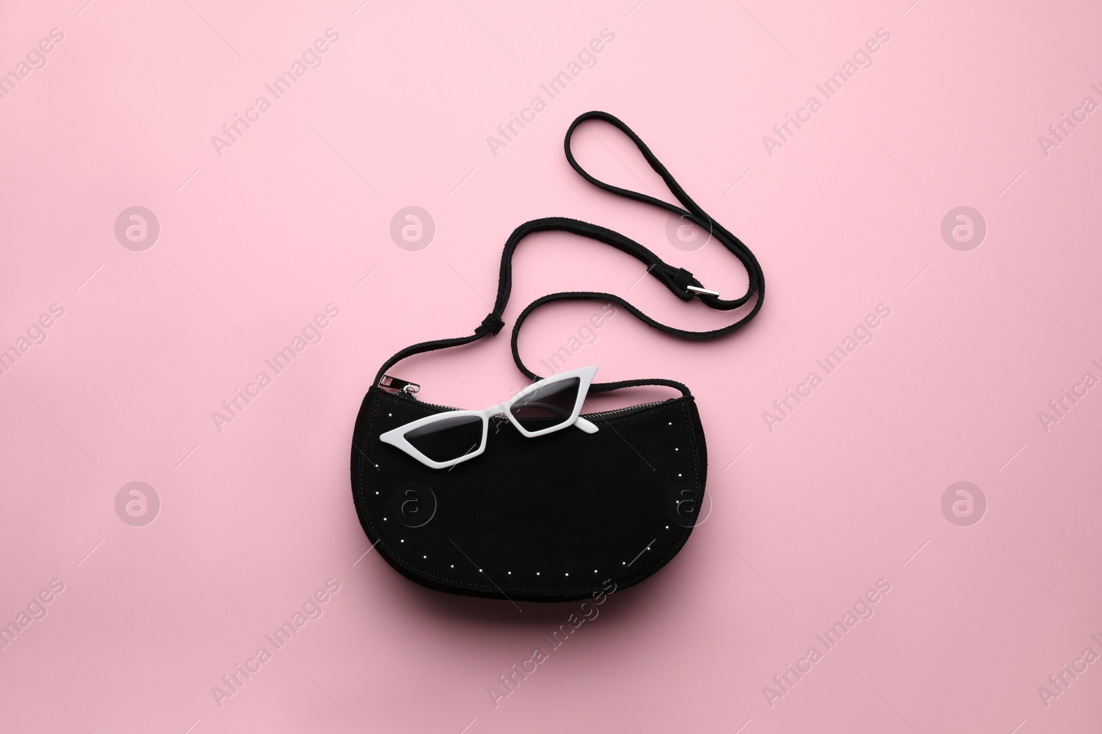 Photo of Stylish woman's bag and sunglasses on pink background, top view