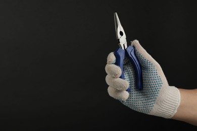 Photo of Man with needle nose pliers on black background, closeup. Space for text