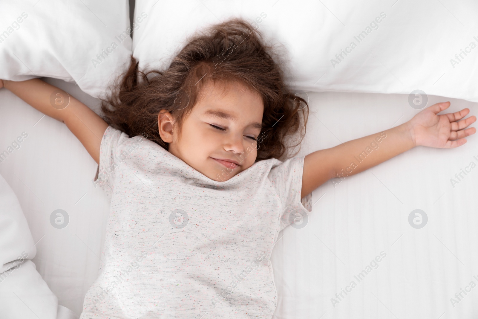 Photo of Cute little girl sleeping on cozy bed, view from above