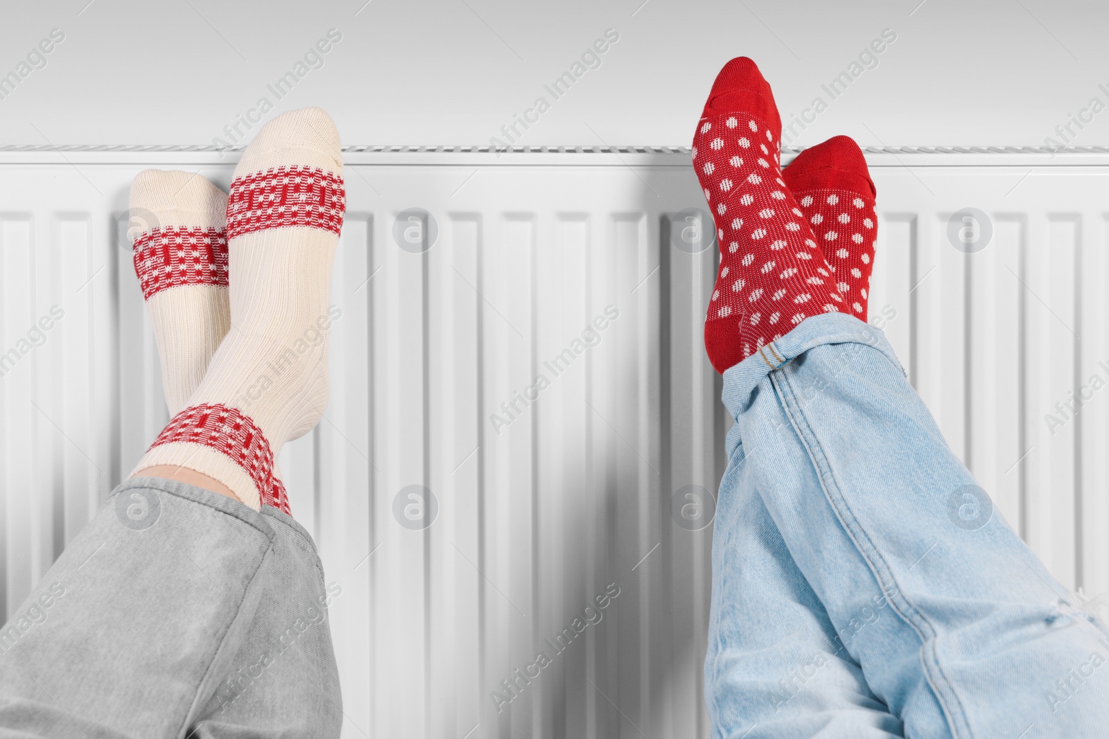 Photo of People warming feet near heating radiator, closeup