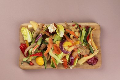 Photo of Peels of fresh vegetables on dusty pink background, top view