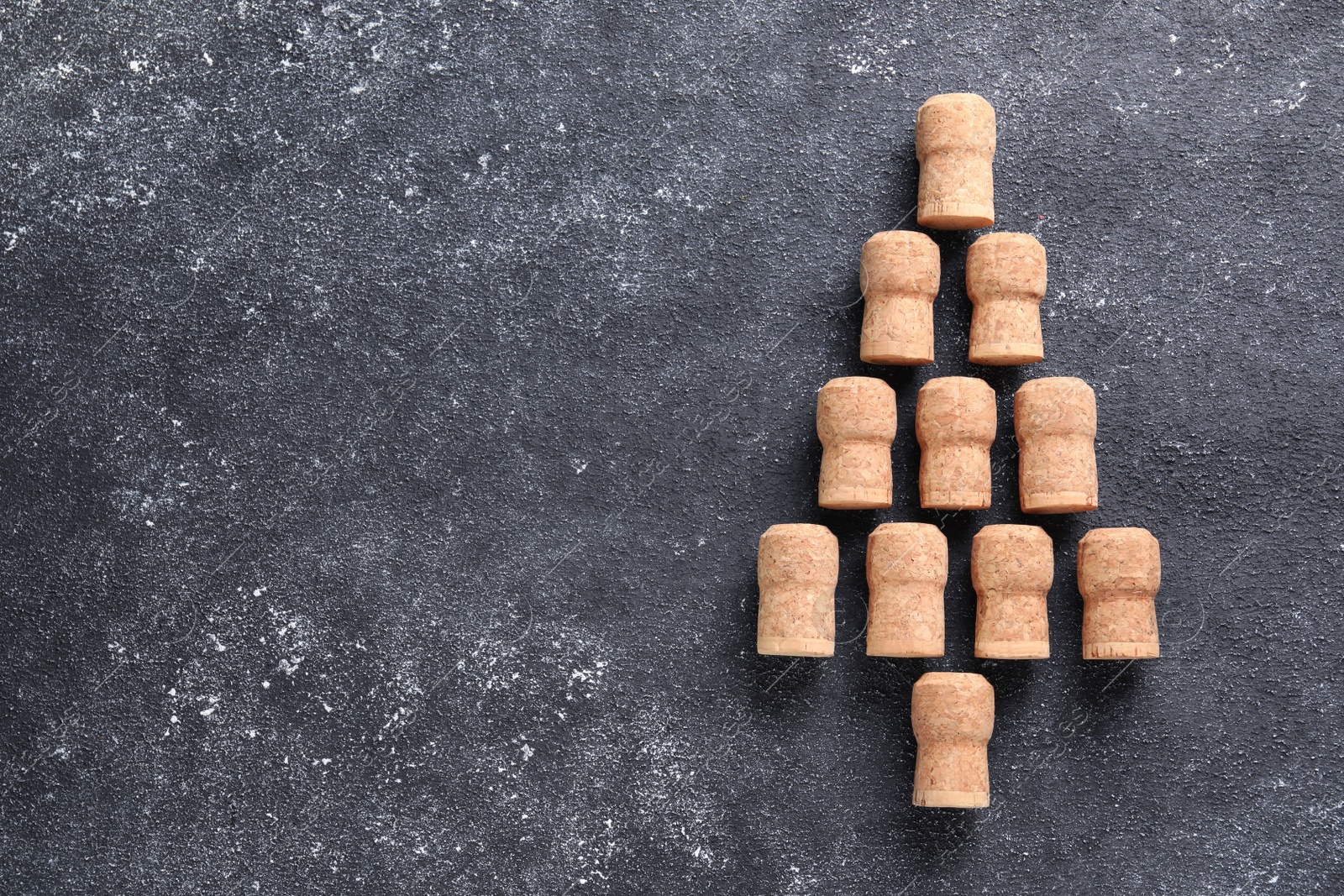 Photo of Christmas tree made of sparkling wine corks on grey table, top view. Space for text