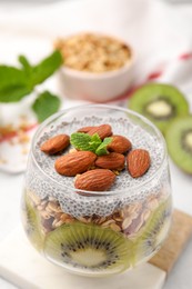Photo of Delicious dessert with kiwi, chia seeds and almonds on table, closeup