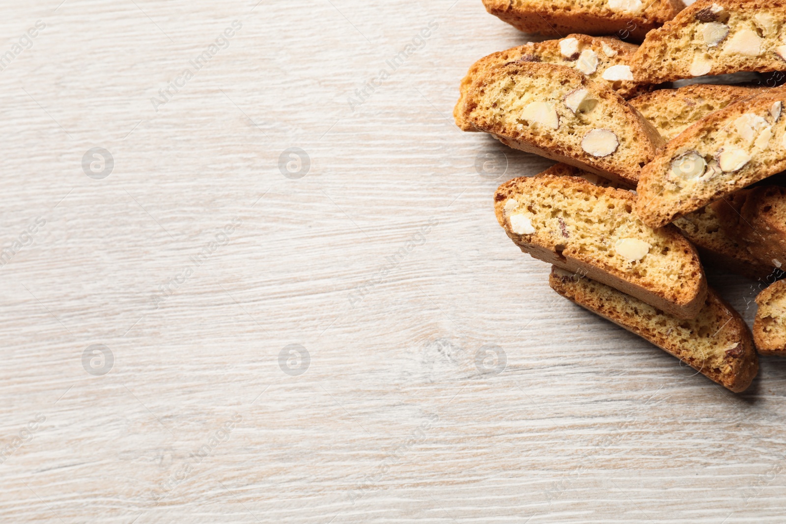 Photo of Traditional Italian almond biscuits (Cantucci) on white wooden table, flat lay. Space for text