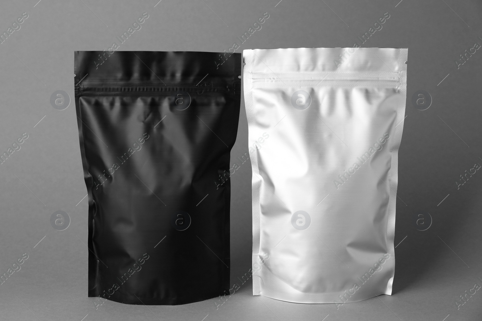 Photo of Different blank foil packages on grey background