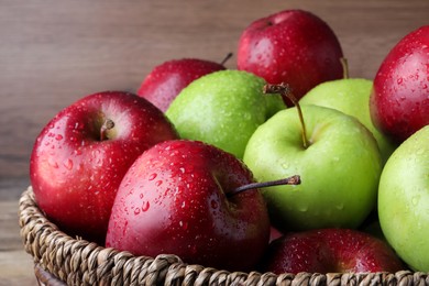 Photo of Fresh ripe green and red apples with water drops in wicker bowl, closeup