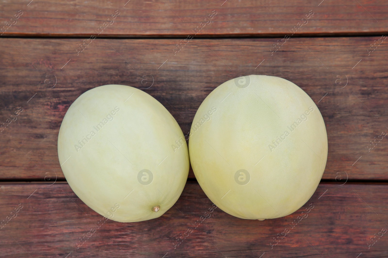 Photo of Whole fresh ripe melons on wooden table, flat lay