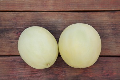 Whole fresh ripe melons on wooden table, flat lay