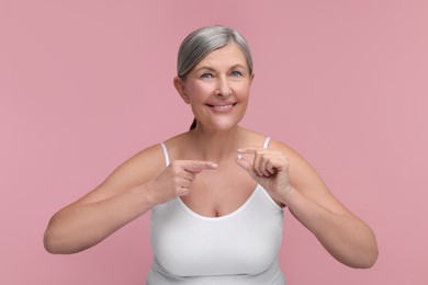 Beautiful woman with vitamin pill on pink background