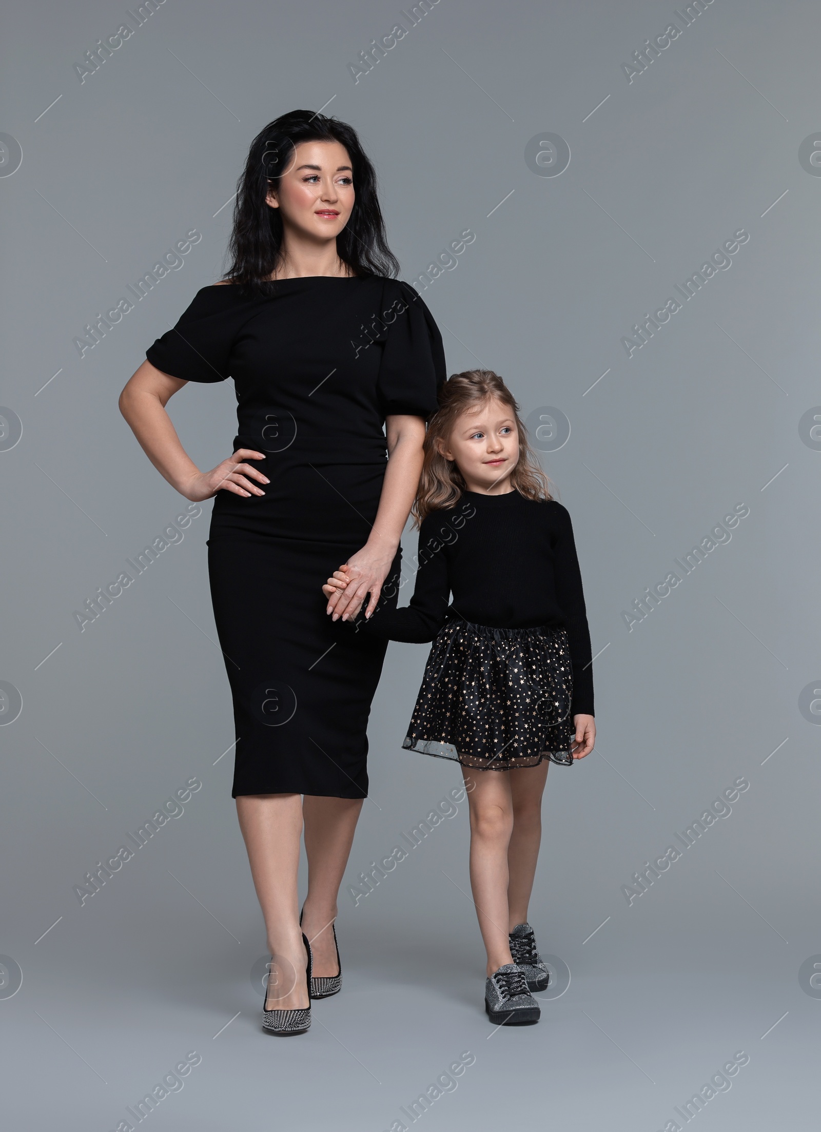 Photo of Beautiful mother with little daughter on grey background. Space for text