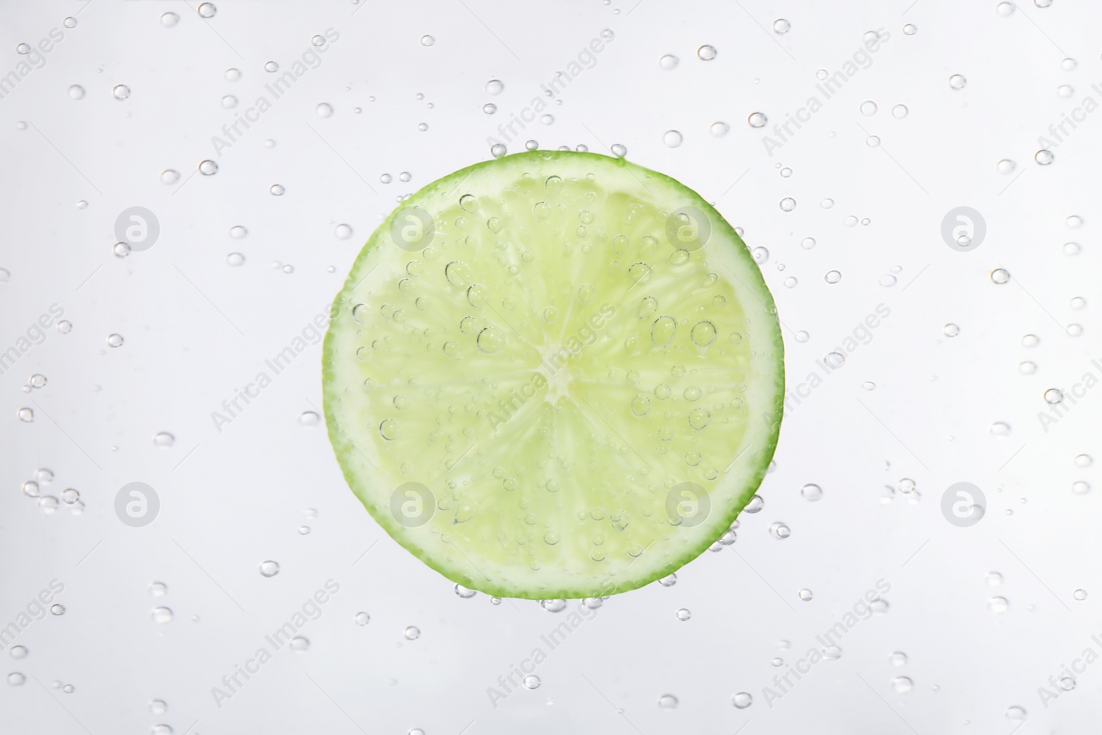 Photo of Juicy lime slice in soda water, closeup