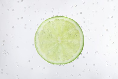 Photo of Juicy lime slice in soda water, closeup