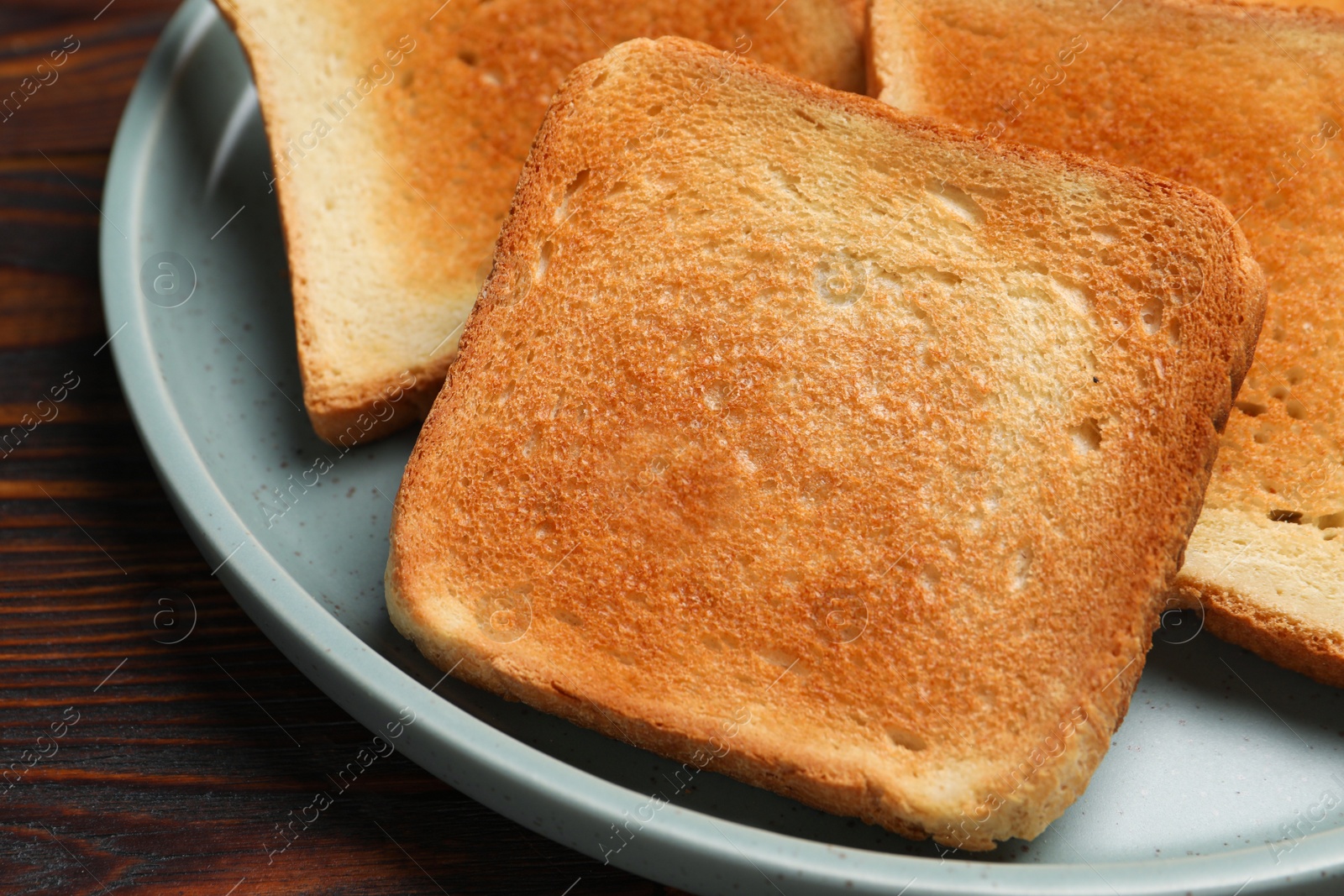 Photo of Slices of tasty toasted bread on wooden table, closeup