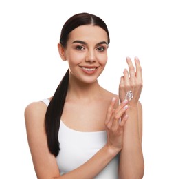 Photo of Young woman applying body cream onto her arm against white background