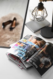 Photo of Open sports magazine and lamp on table indoors
