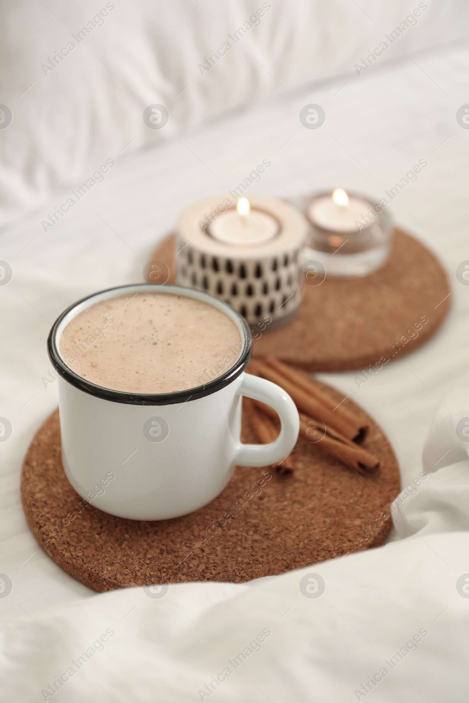 Photo of Cup of aromatic coffee on bed with soft blanket, closeup