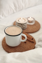 Cup of aromatic coffee on bed with soft blanket, closeup