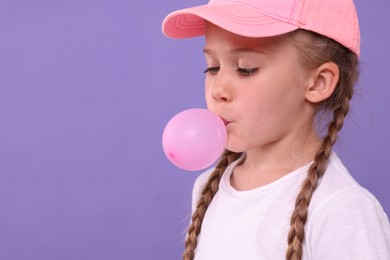Photo of Girl blowing bubble gum on purple background, space for text