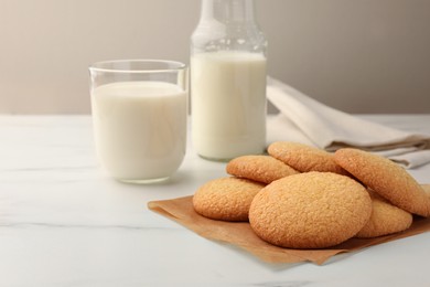 Photo of Delicious Danish butter cookies and milk on white marble table, closeup. Space for text