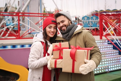 Photo of Lovely couple with Christmas presents in amusement park