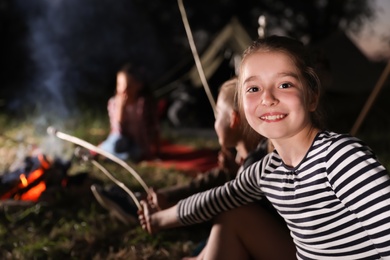 Adorable little girl near bonfire at night. Summer camp