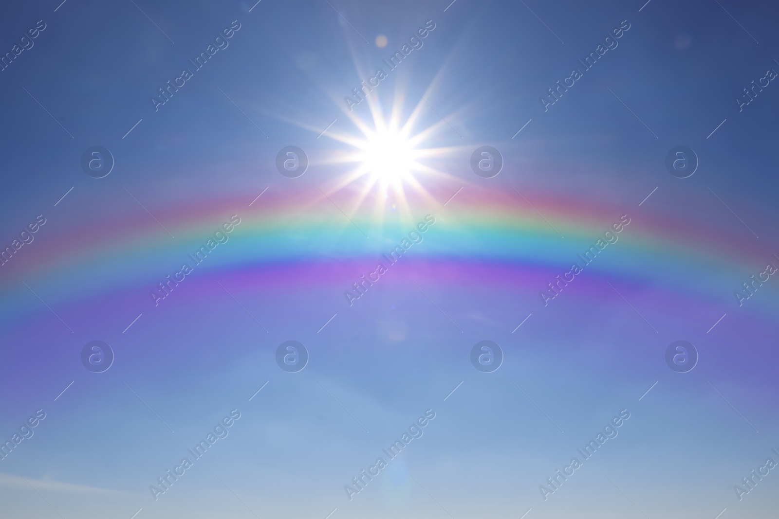 Image of Beautiful view of bright rainbow in blue sky on sunny day