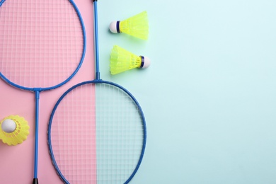 Photo of Badminton rackets and shuttlecocks on color background, flat lay. Space for text