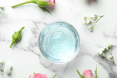 Photo of Flat lay composition with cosmetic gel and beautiful flowers on white marble table