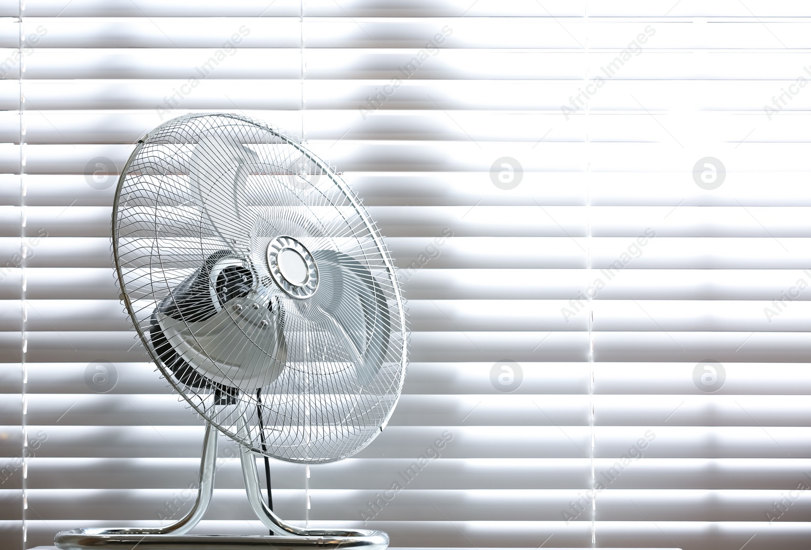 Photo of Modern electric fan on table near window indoors. Space for text