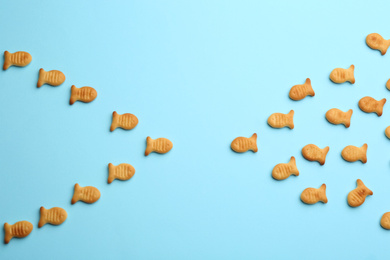 Photo of Delicious goldfish crackers on light blue background, flat lay