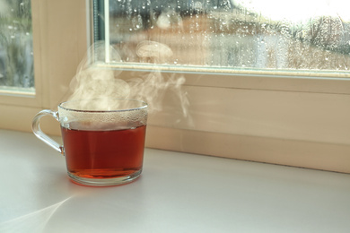 Photo of Cup of hot tea near window on rainy day.  Space for text
