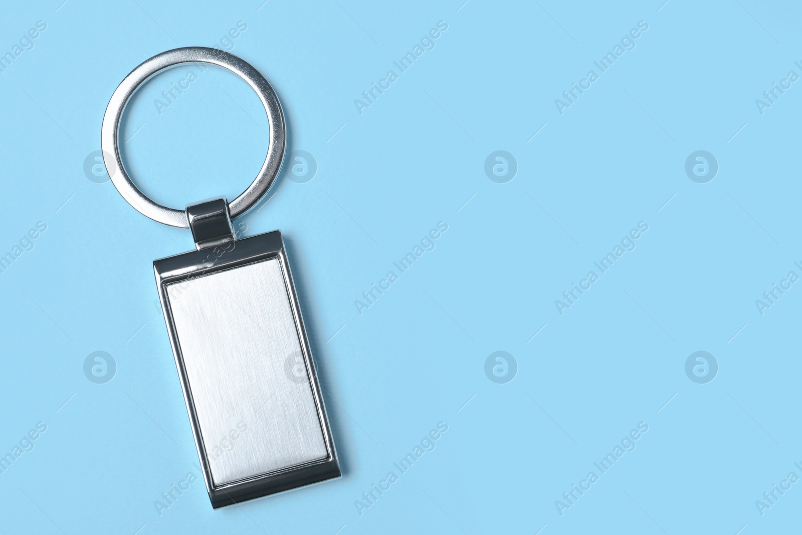 Photo of Metallic keychain on light blue background, top view. Space for text