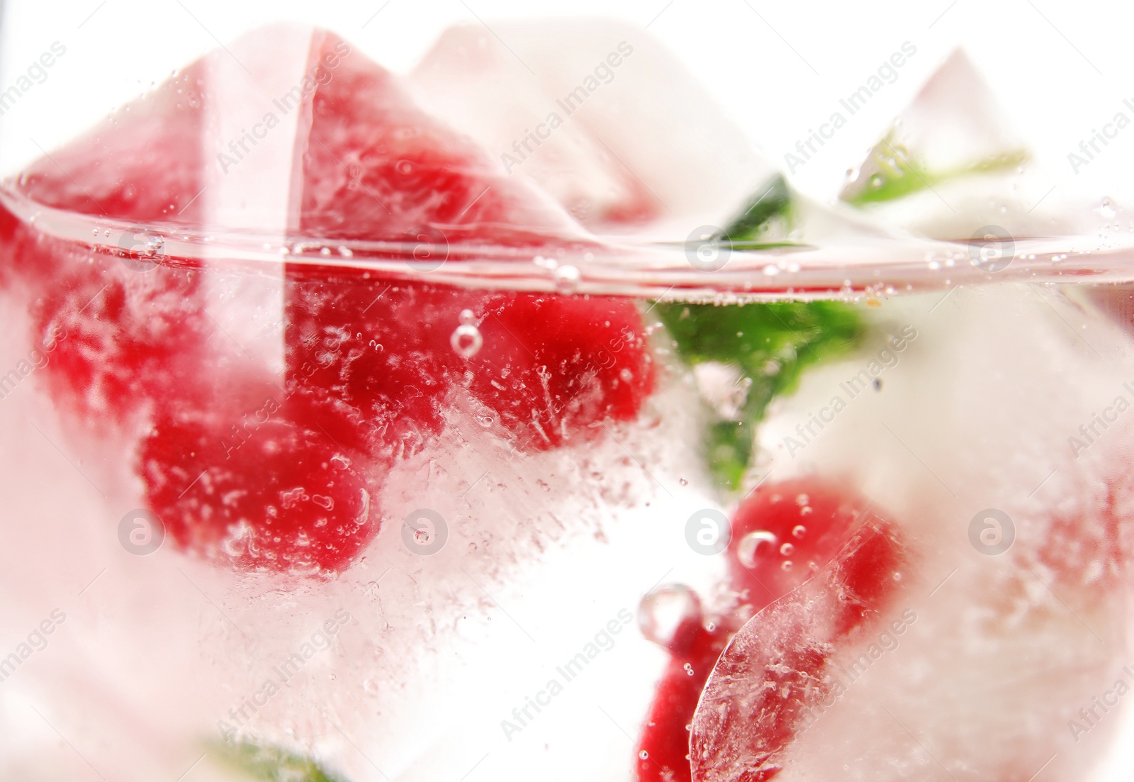 Photo of Drink with pomegranate ice cubes in glass, closeup