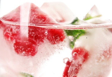 Photo of Drink with pomegranate ice cubes in glass, closeup