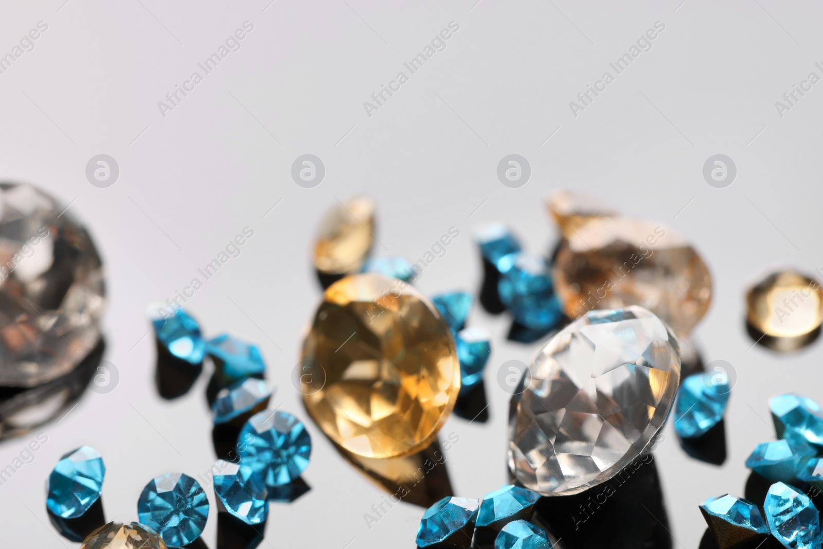 Photo of Different beautiful gemstones for jewelry on mirror surface, closeup. Space for text
