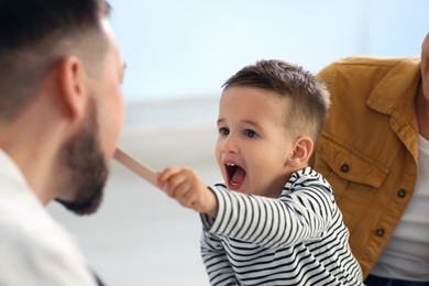 Photo of Mother and son visiting pediatrician in hospital. Doctor playing with little boy