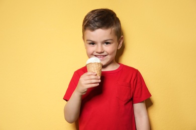 Photo of Adorable little boy with delicious ice cream against color background