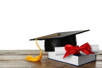 Graduation hat, book and diploma on wooden table against white background