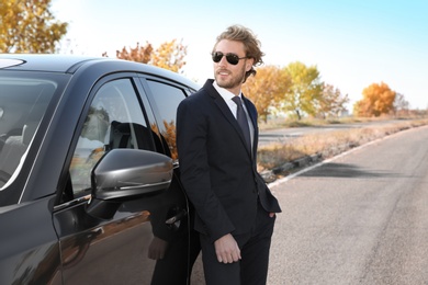 Photo of Young businessman near modern car on sunny day, outdoors