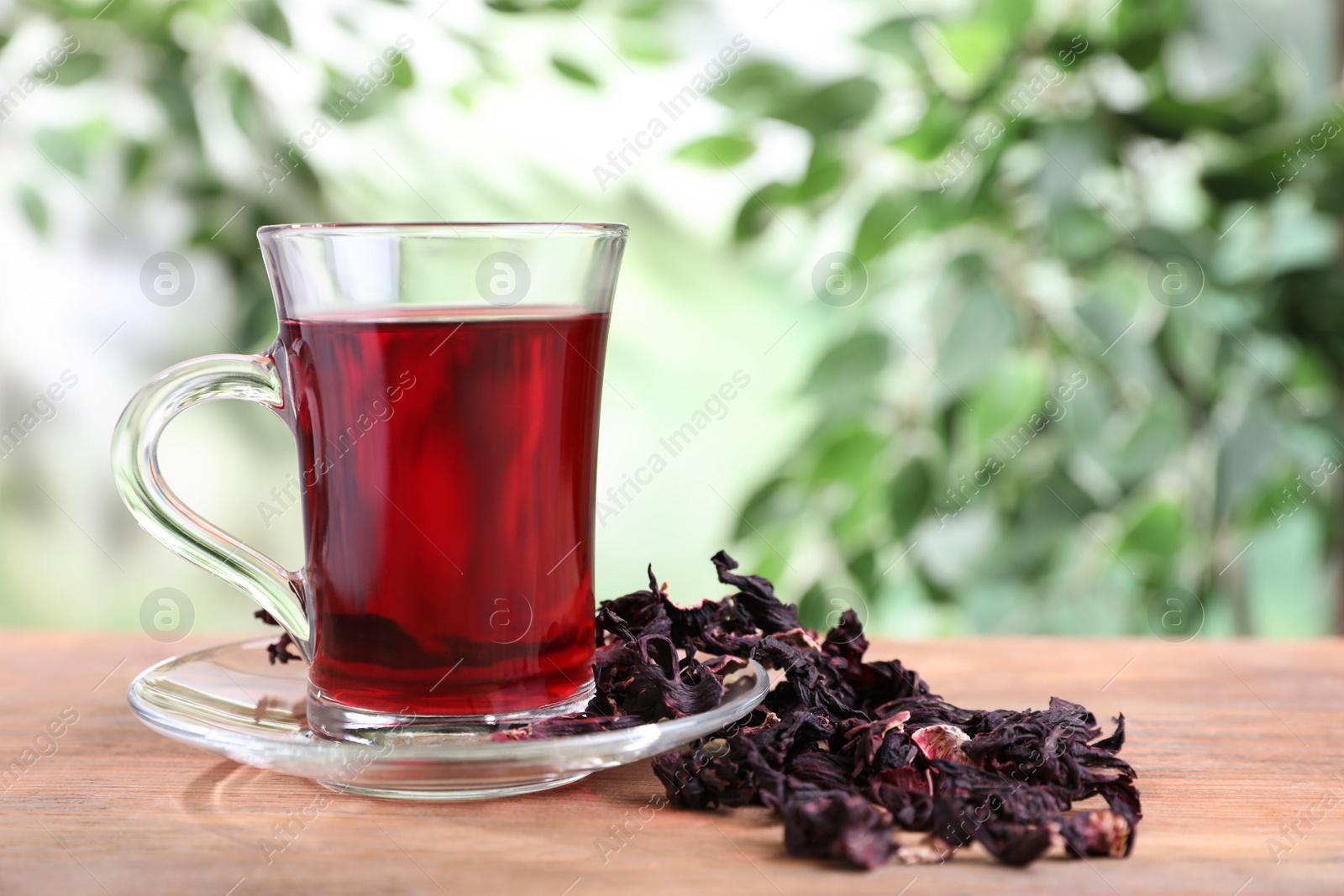 Photo of Fresh Hibiscus tea on wooden table against blurred background. Space for text