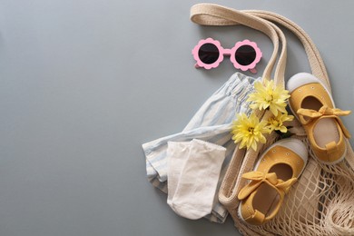 Photo of Stylish child clothes, flowers and accessories on grey background, flat lay. Space for text