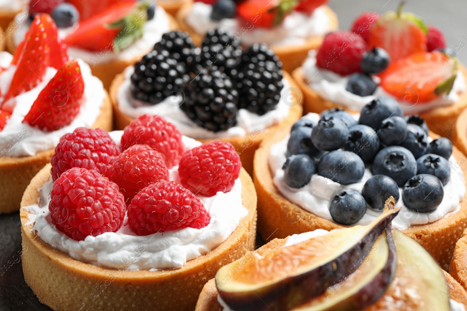 Photo of Many different berry tarts on table, closeup. Delicious pastries