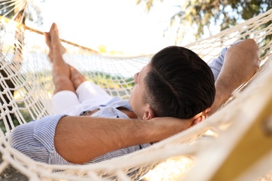 Photo of Man relaxing in hammock on beach. Summer vacation