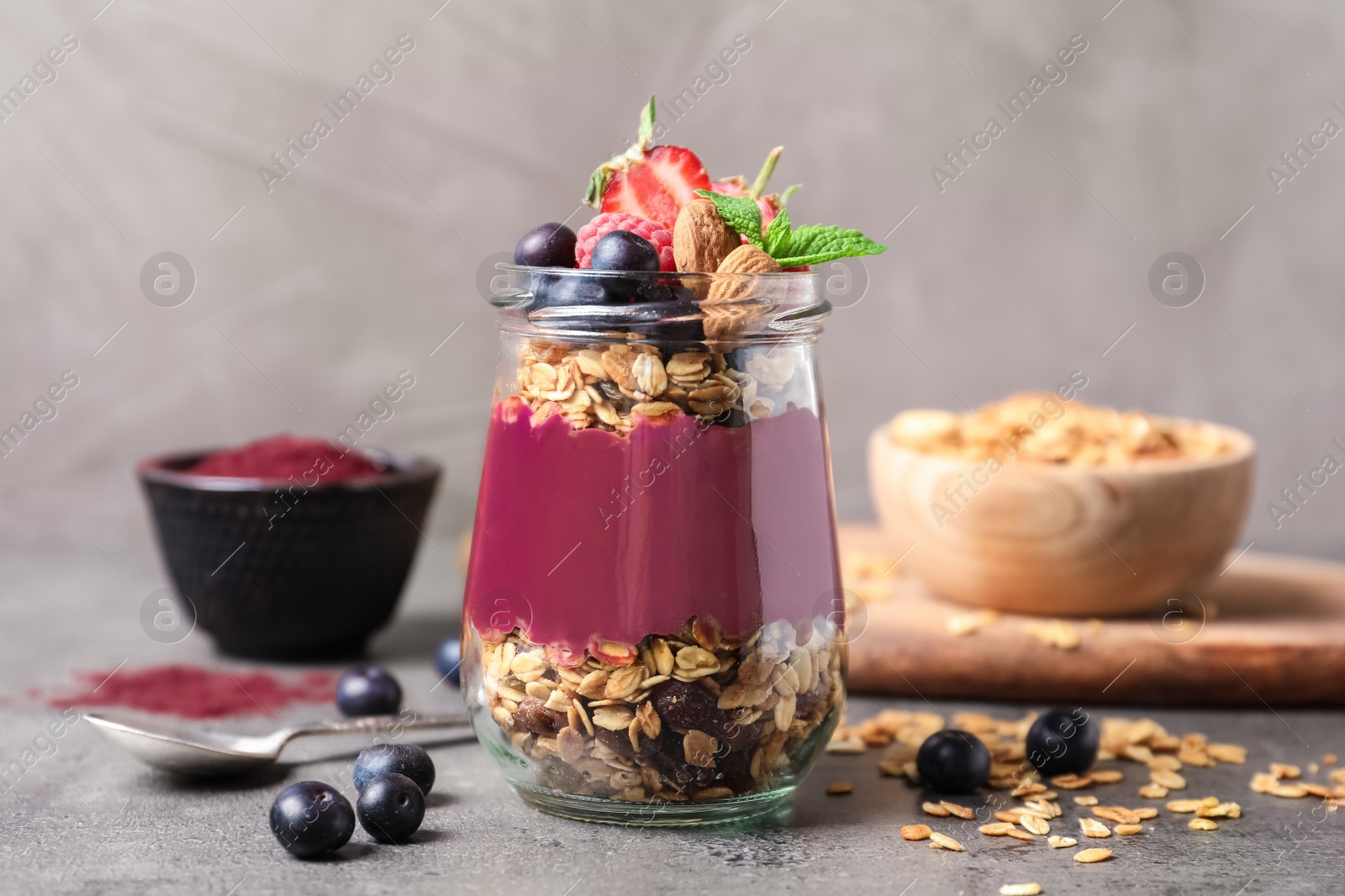 Photo of Delicious acai dessert with granola and berries served on grey table