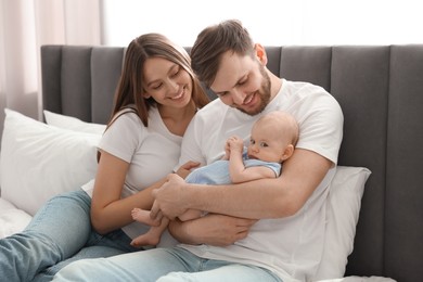Photo of Happy family. Parents with their cute baby on bed indoors
