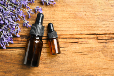 Flat lay composition with lavender flowers and essential oil on wooden background. Space for text