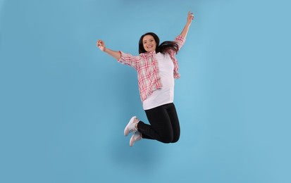 Photo of Beautiful overweight woman jumping on turquoise background
