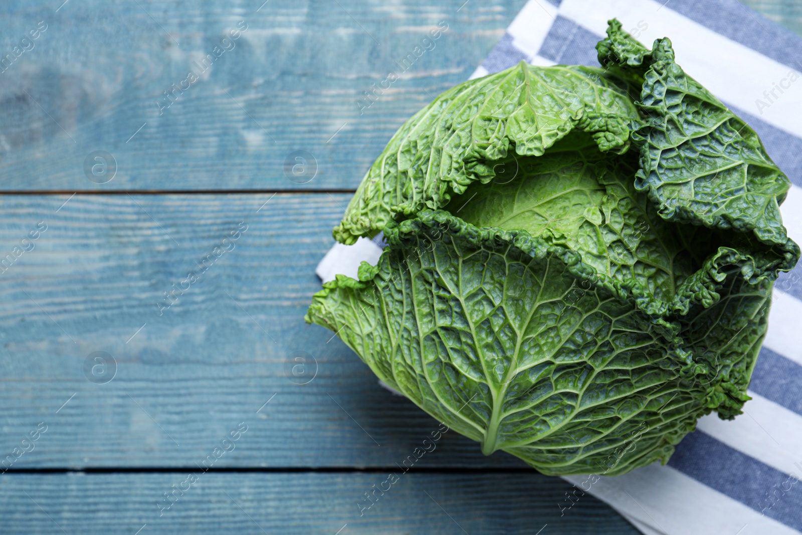 Photo of Fresh ripe savoy cabbage on blue wooden table, top view. Space for text