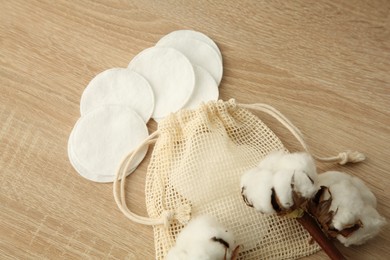 Photo of Cotton pads, bag and flowers on wooden table