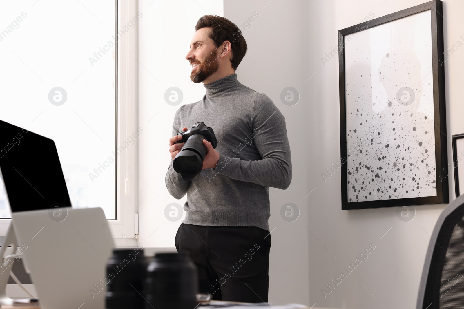 Photo of Professional photographer with digital camera near window indoors